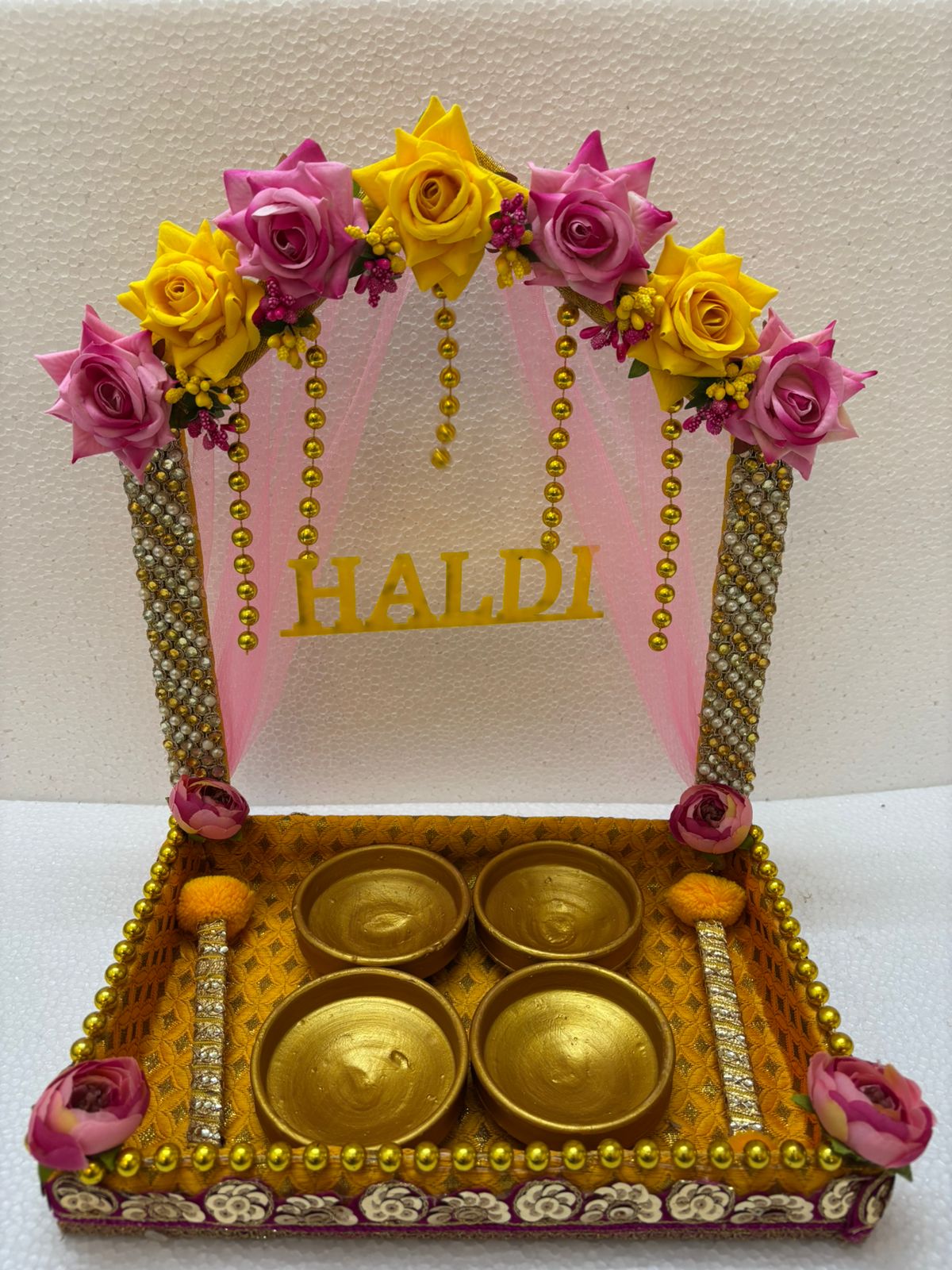 Handmade Haldi Platter decorated with pink and yellow flowers, golden beads, and four golden bowls for wedding and festive rituals