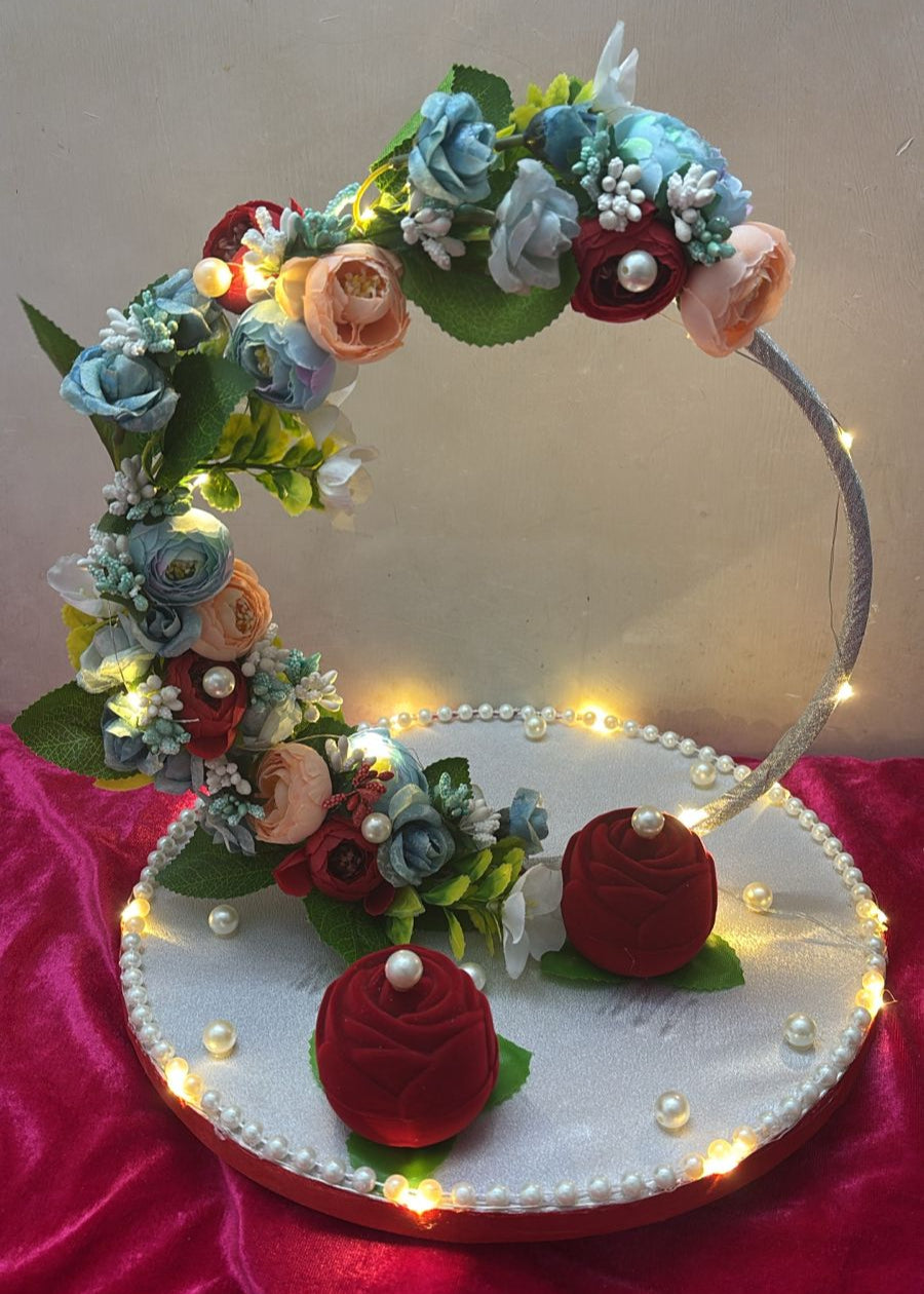 A decorative ring platter with a handmade, round design, featuring a colorful floral arrangement and pearls, with LED lights around the perimeter.