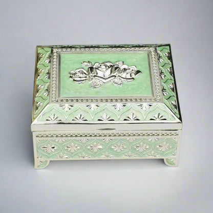 A sea green enamel jewelry box with a floral design on the lid and silver detailing