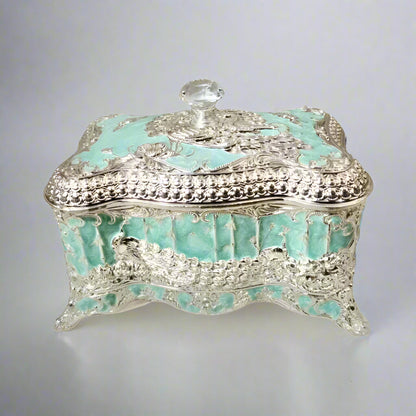 A blue enamel jewelry box with silver detailing and a lid, placed on a solid background.