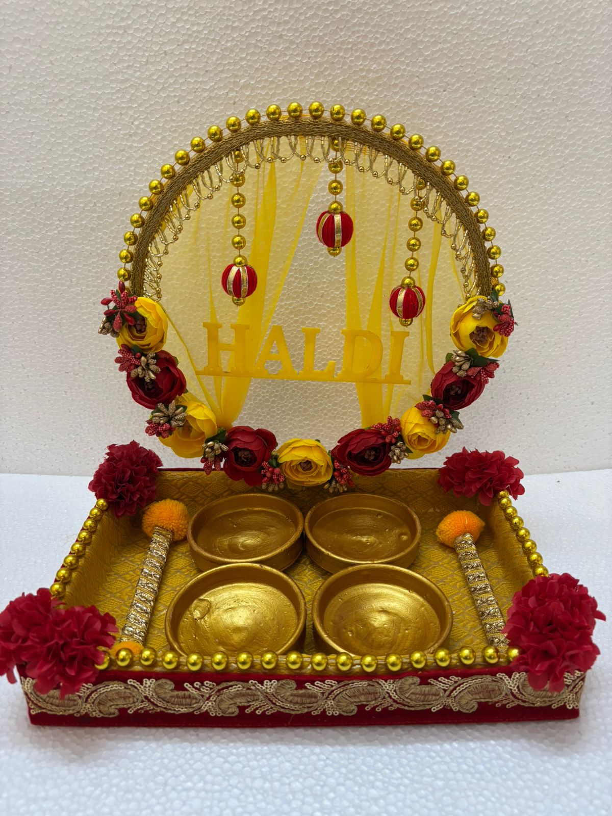 Handmade Haldi Platter decorated with red and yellow flowers, golden beads, and four golden bowls for wedding ceremony rituals