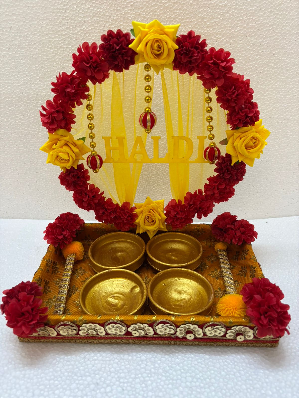 Handmade Haldi Platter decorated with red and yellow flowers, golden beads, and four golden bowls for wedding and festive rituals