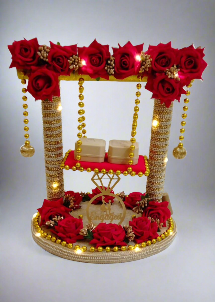 A decorative ring platter with a golden finish, adorned with red roses and golden beads, used for ring ceremony purposes.